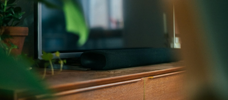 Close-up van een elegante, donkere soundbar op een houten meubel.