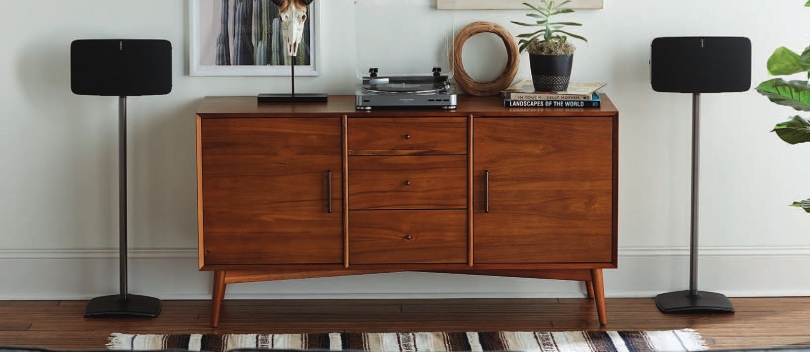 Twee Harman Kardon speakers op een speaker standaard naast een houten dressoir