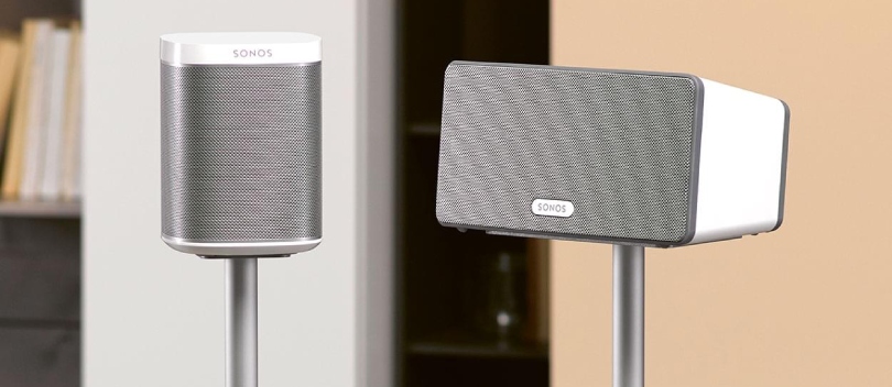 Twee witte sonos speakers op een speaker sandaard in dezelfde kleur als de speakers