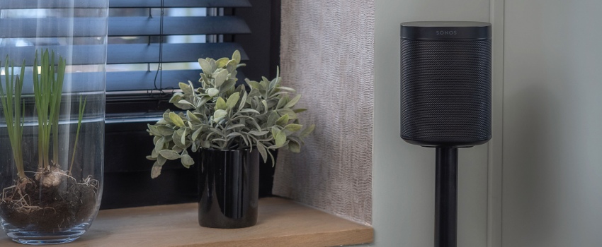 Compacte zwarte speaker op een slanke standaard in de hoek van een ruimte