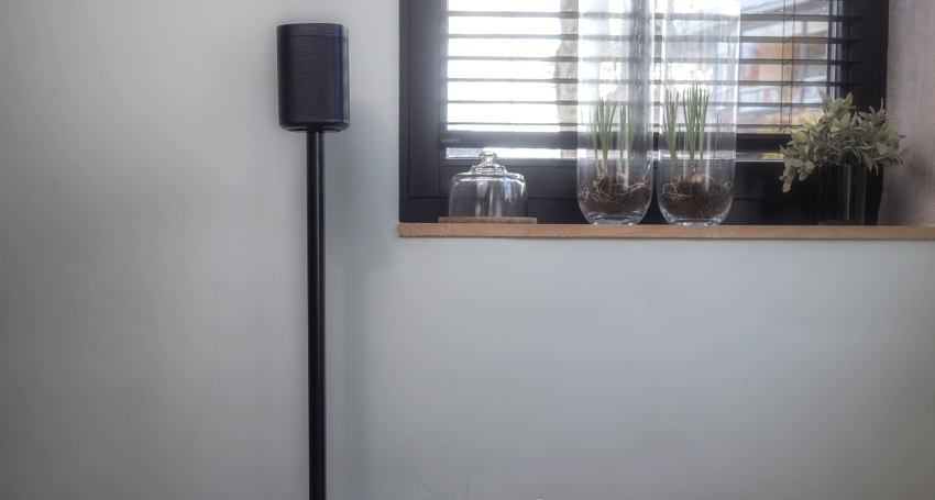 Zwarte speaker op statief naast raam met planten