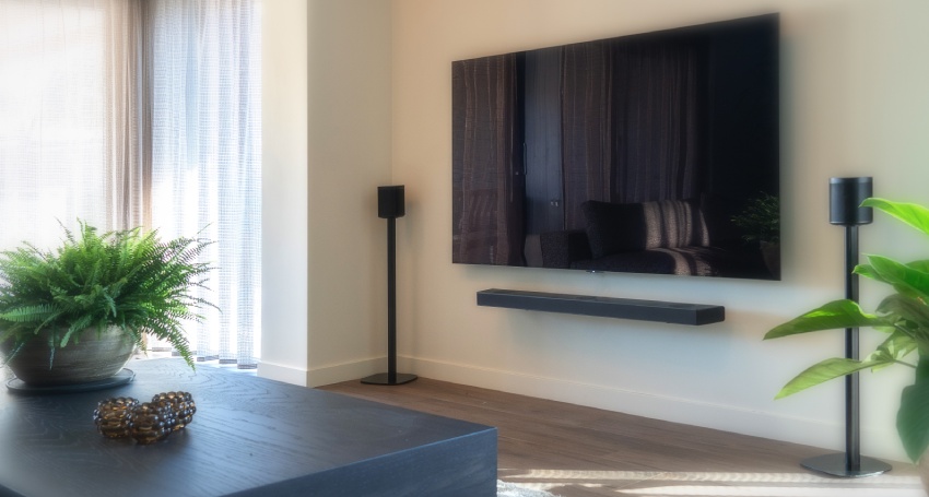 Moderne woonkamer met twee zwarte speaker statieven naast een flatscreen tv