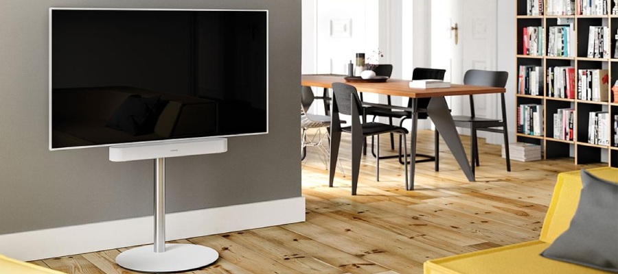 woonkamer met op de voorgrond een televisie geplaatst op een tv standaard. In de achtergrond staat een gevulde boekenkast en een zittafel met stoelen